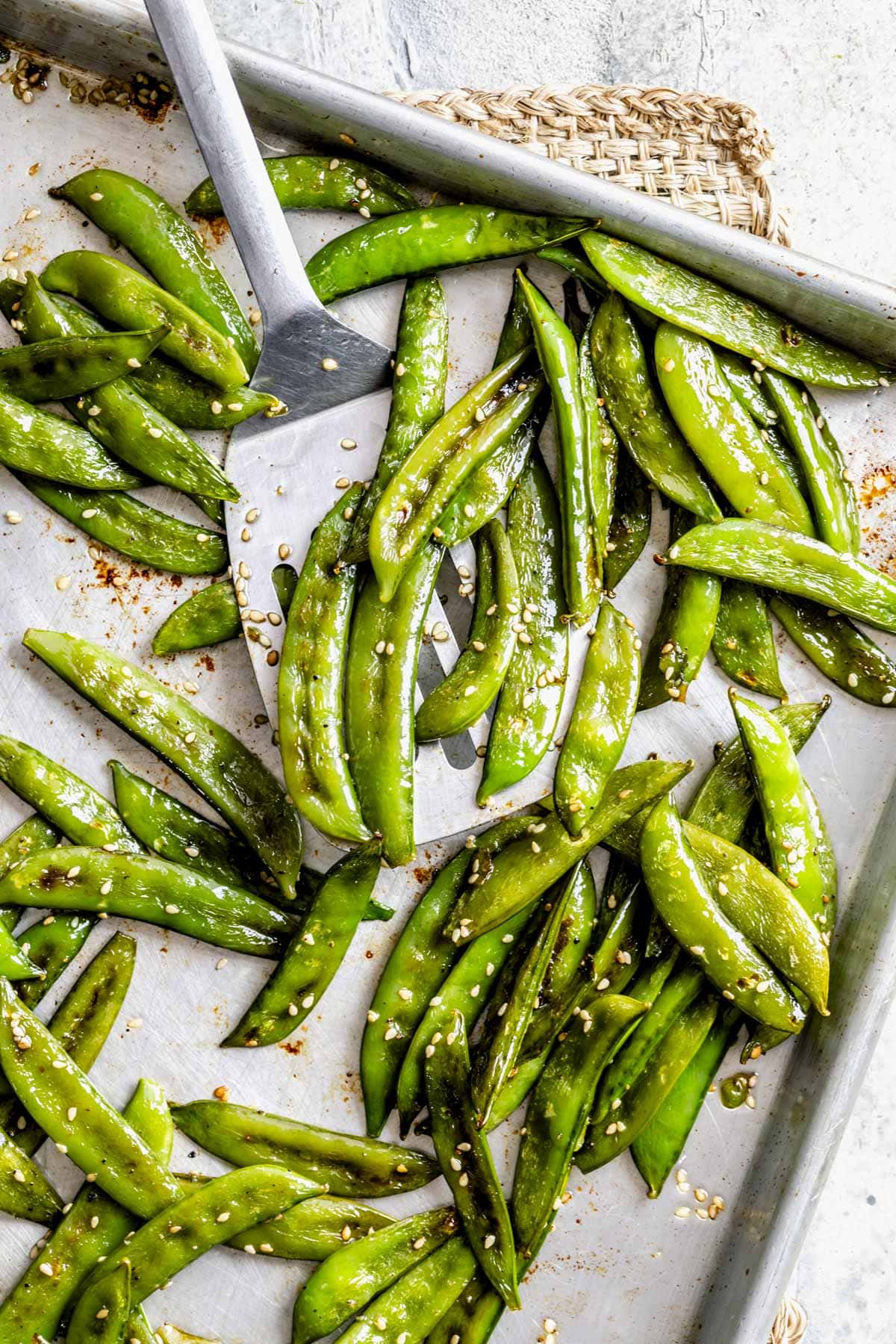 a spatula full of the snap peas on the sheet pan