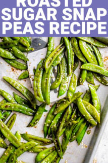 the roasted snap peas on a sheet pan with a spatula and sesame seeds