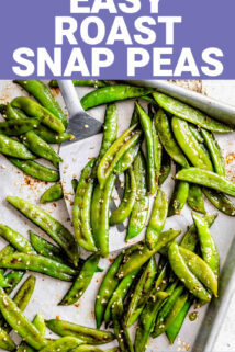 the roasted snap peas on a sheet pan with a spatula and sesame seeds