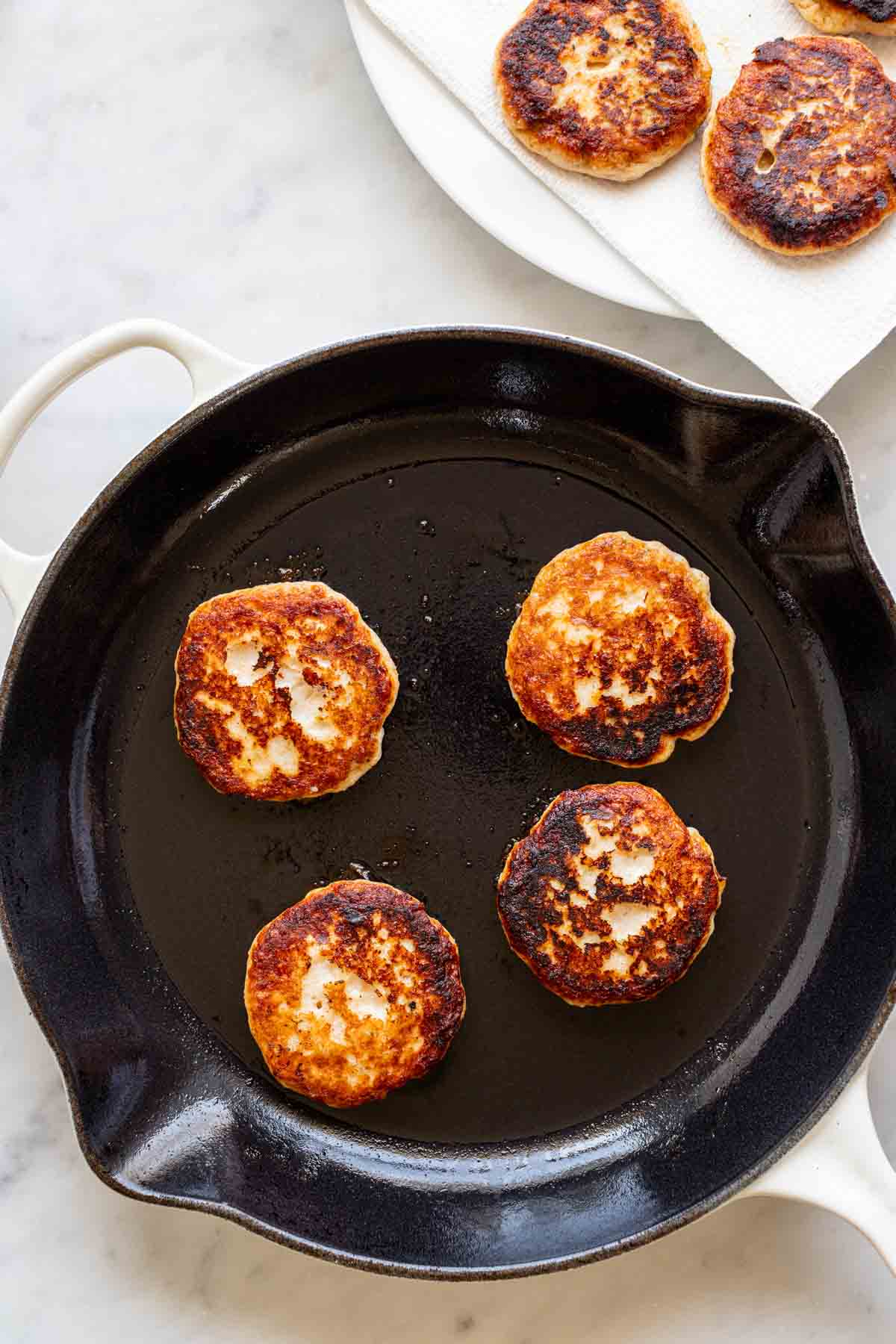 frying the thai fish cakes in a skillet with coconut oil