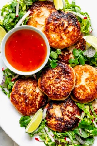 amazingly golden brown fried fish cakes on a platter with herbal salad and dipping sauce