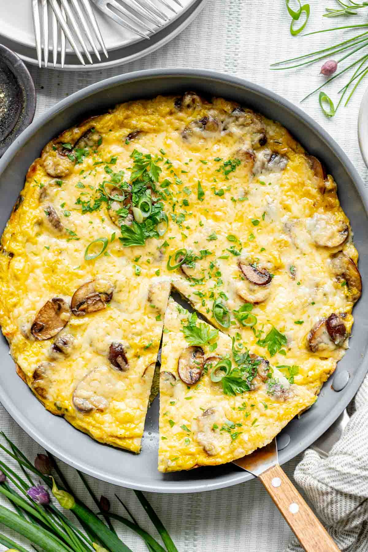 mushroom frittata in a skillet with a single wedge cut out