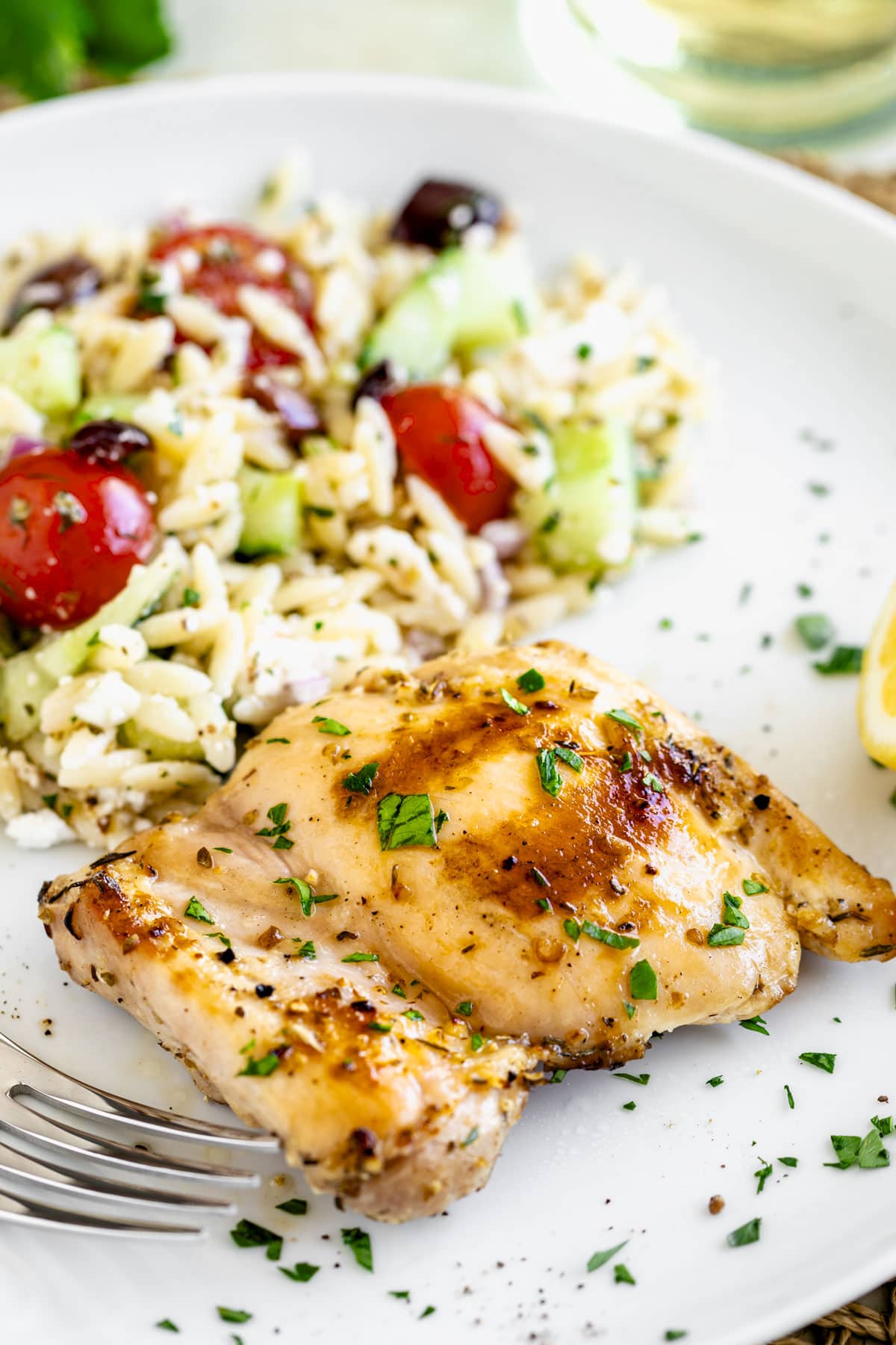a close-up of the boneless chicken thigh on a plate with orzo salad