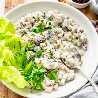 healthy chicken salad in a large white bowl with butter lettuce leaves on the side