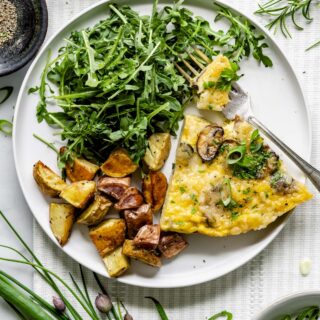 the frittata on a white plate with salad and homefries