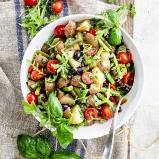 the potato salad with green beans in a white bowl