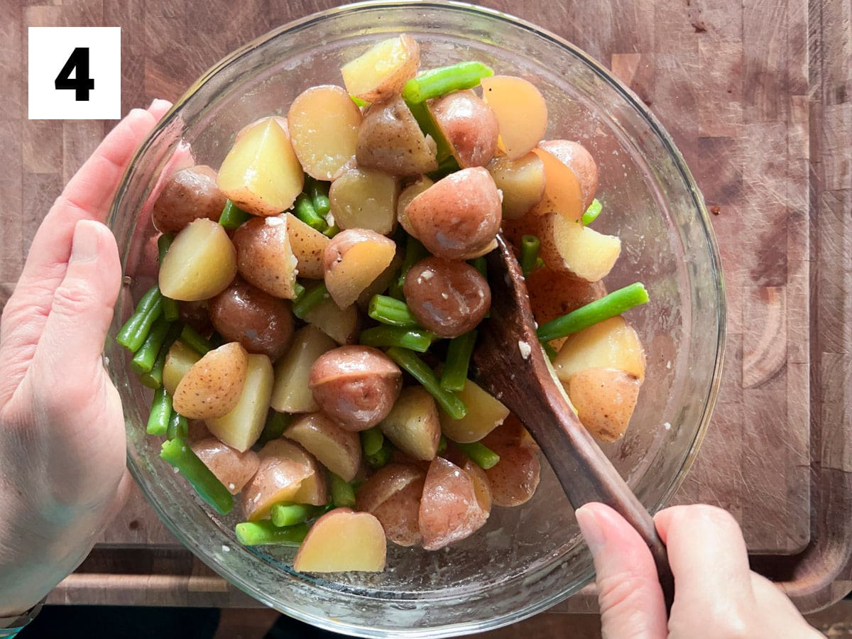 stirring the potatoes and green beans into the dressing
