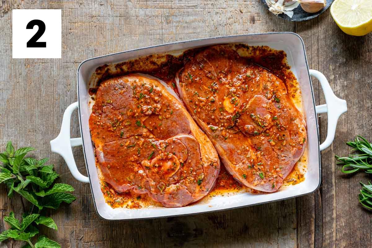 two lamb steaks covered with the marinade in the shallow dish
