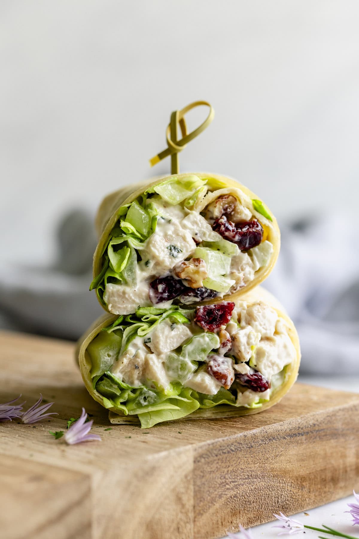 a chicken salad wrap cut in half and stacked on a wooden cutting board