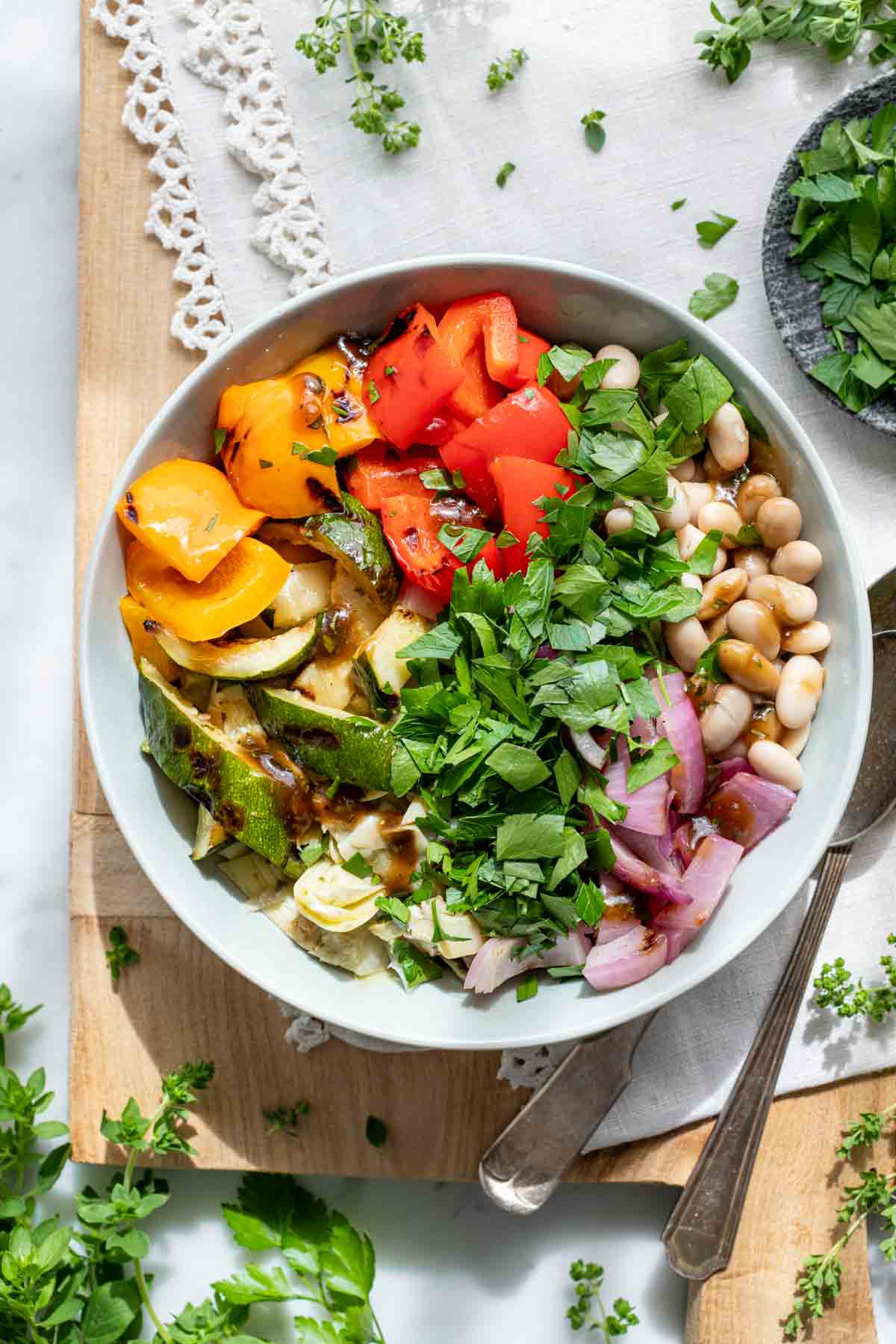 tossed and dressed grilled veggie salad with white beans in circular white bowl