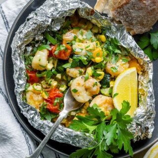 a foil packet full of shrimp, veggies, seasonings, and herbs