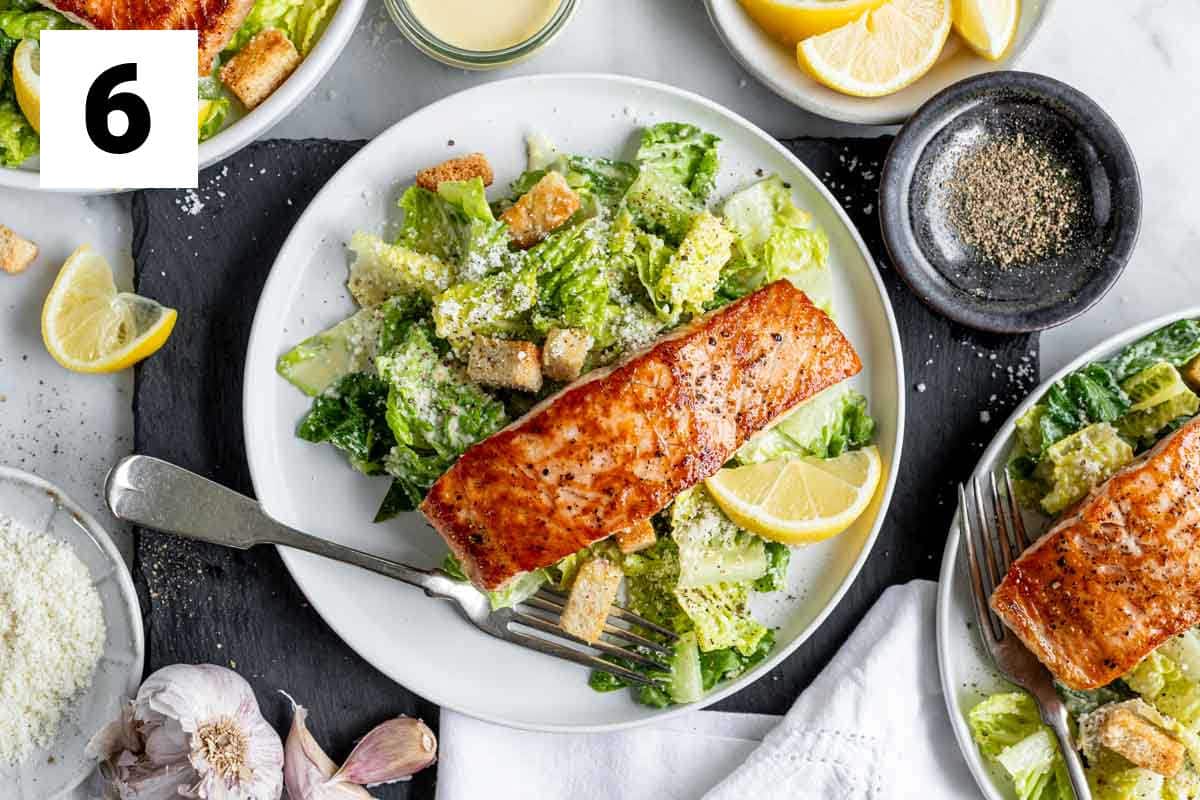 a plate with the salmon on top of the salad with a fork on the plate