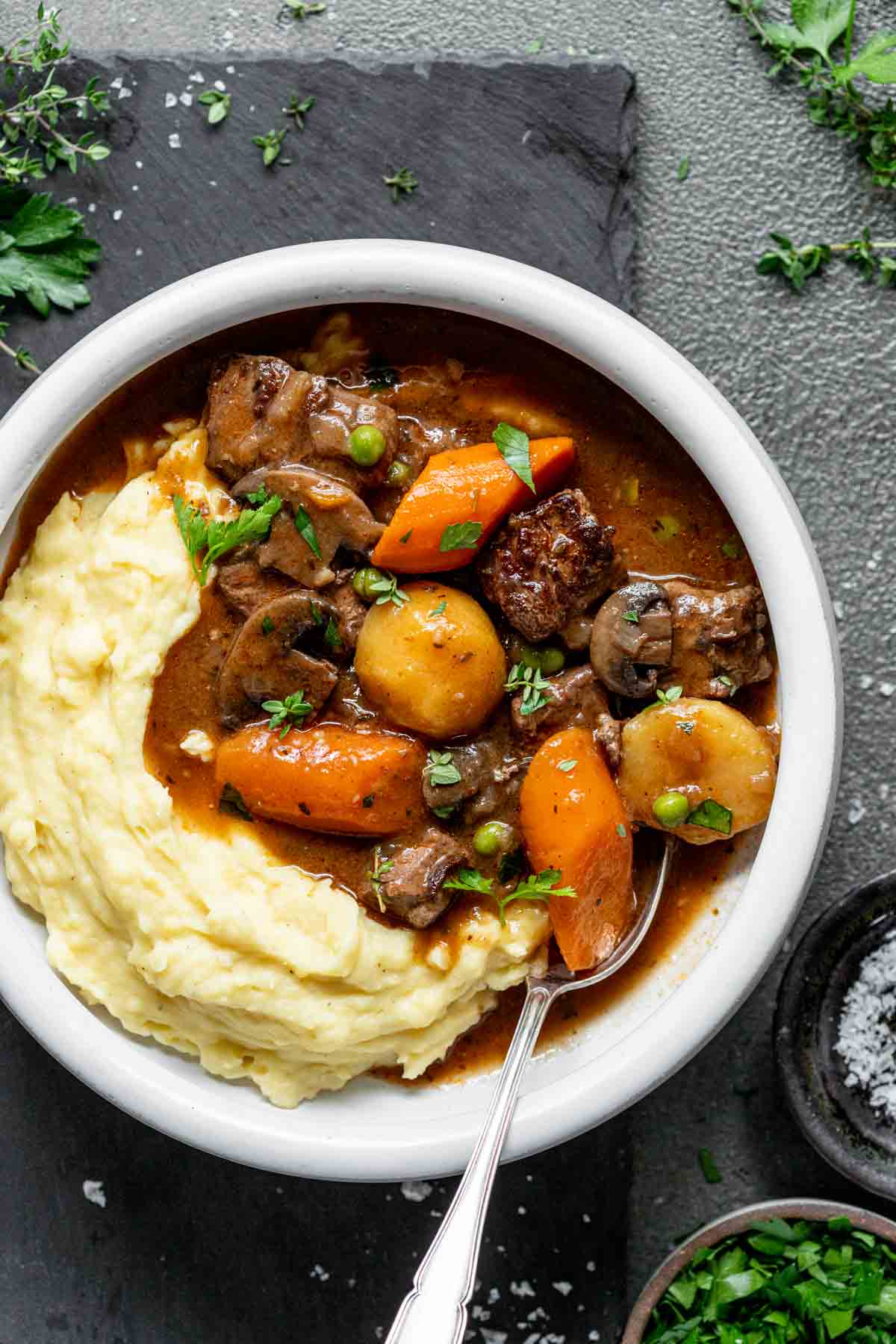 the stew in a white bowl with mashed potatoes