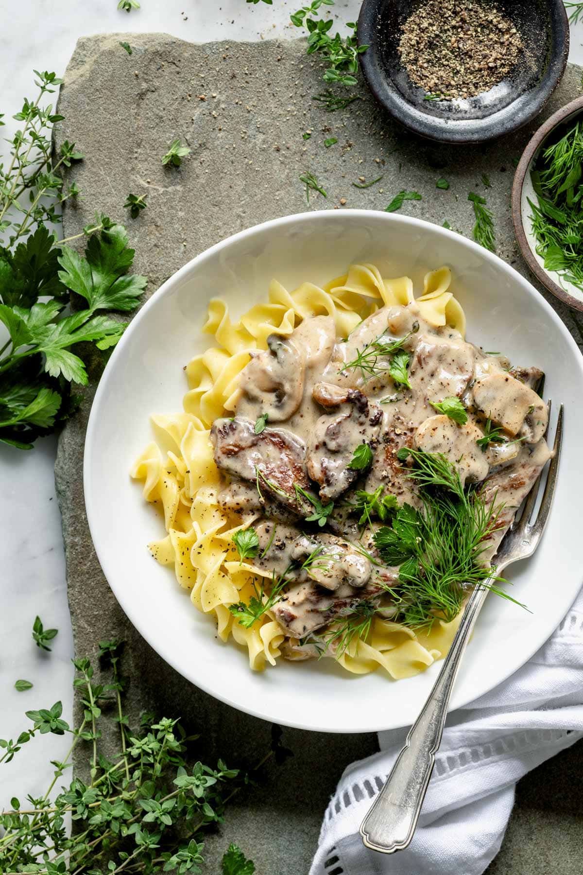 beef stroganoff served over pasta in circular white dish