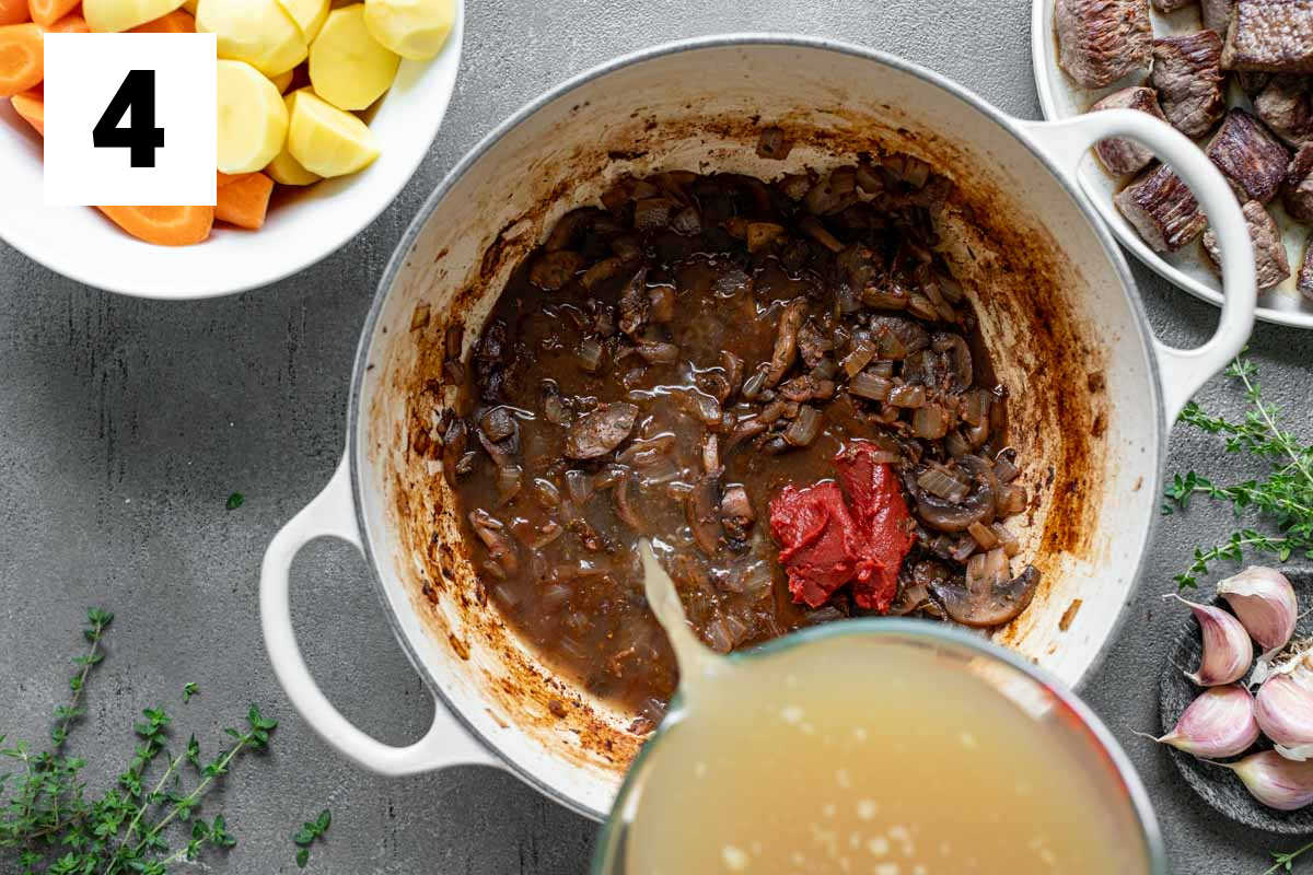 adding the broth to the pot with the tomato paste