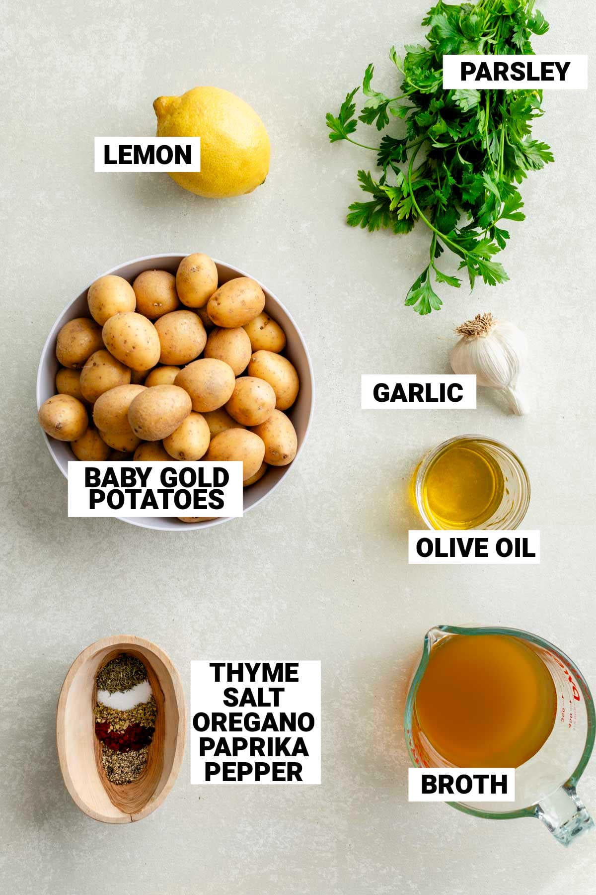 the ingredients for the roasted potatoes laid out on a white table top with text overlay labeling each item