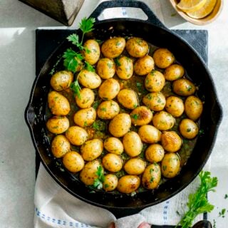 baby potatoes in a cast iron skillet with parsley sprigs and lemon