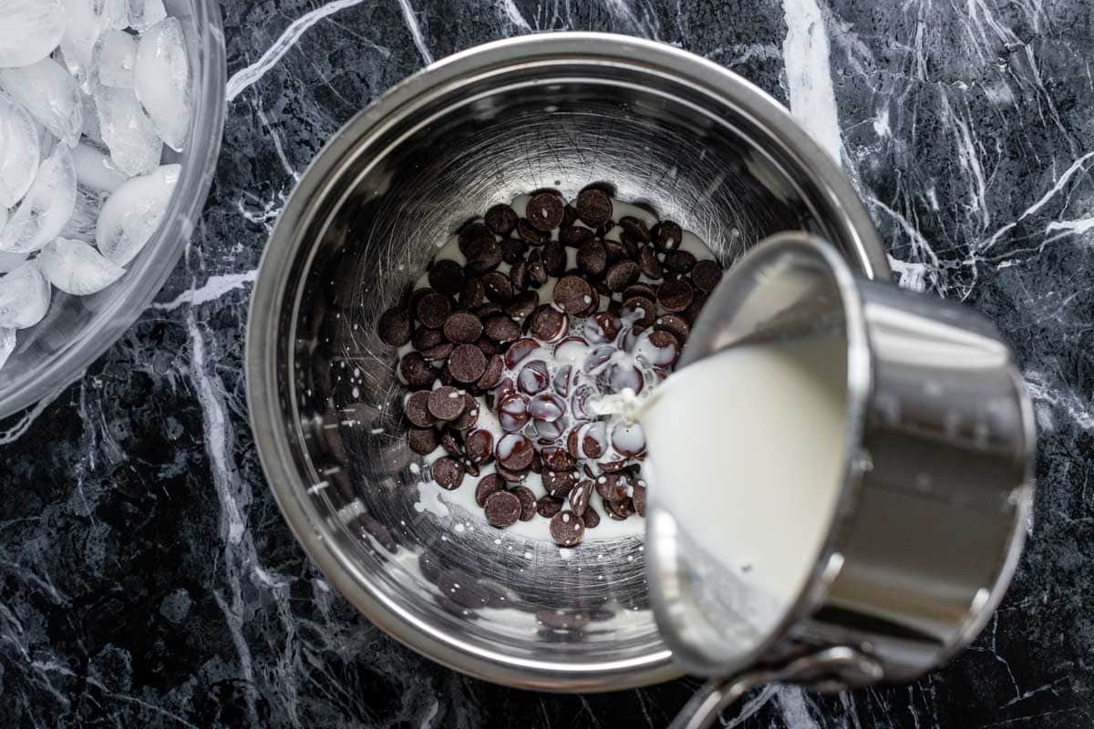 pouring the half and half over the chocolate chips to make the ganache frosting