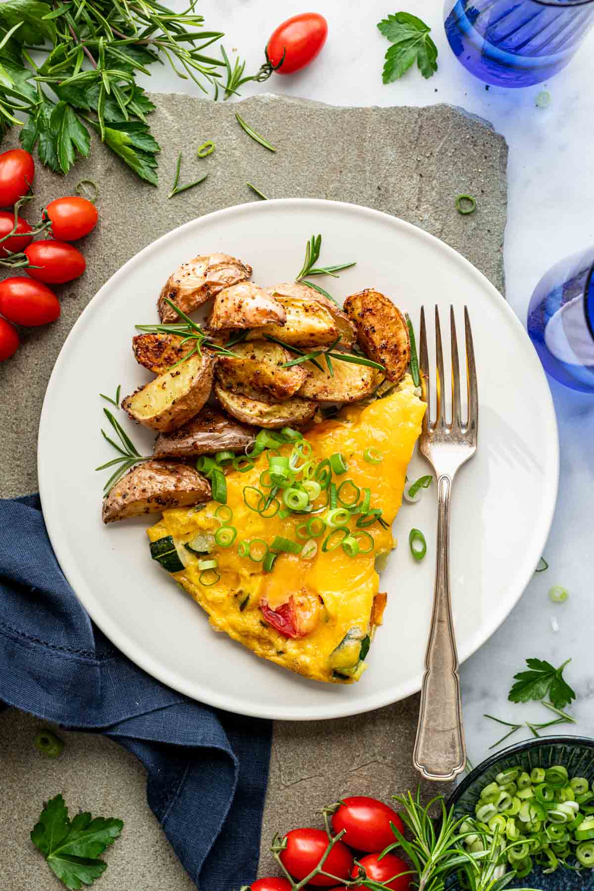 a slice of the frittata on a white plate with brunch potatoes