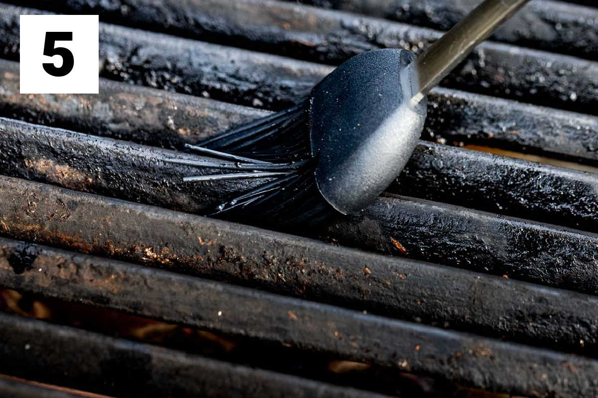 a grill brush sliding along the grates of the grill to oil it
