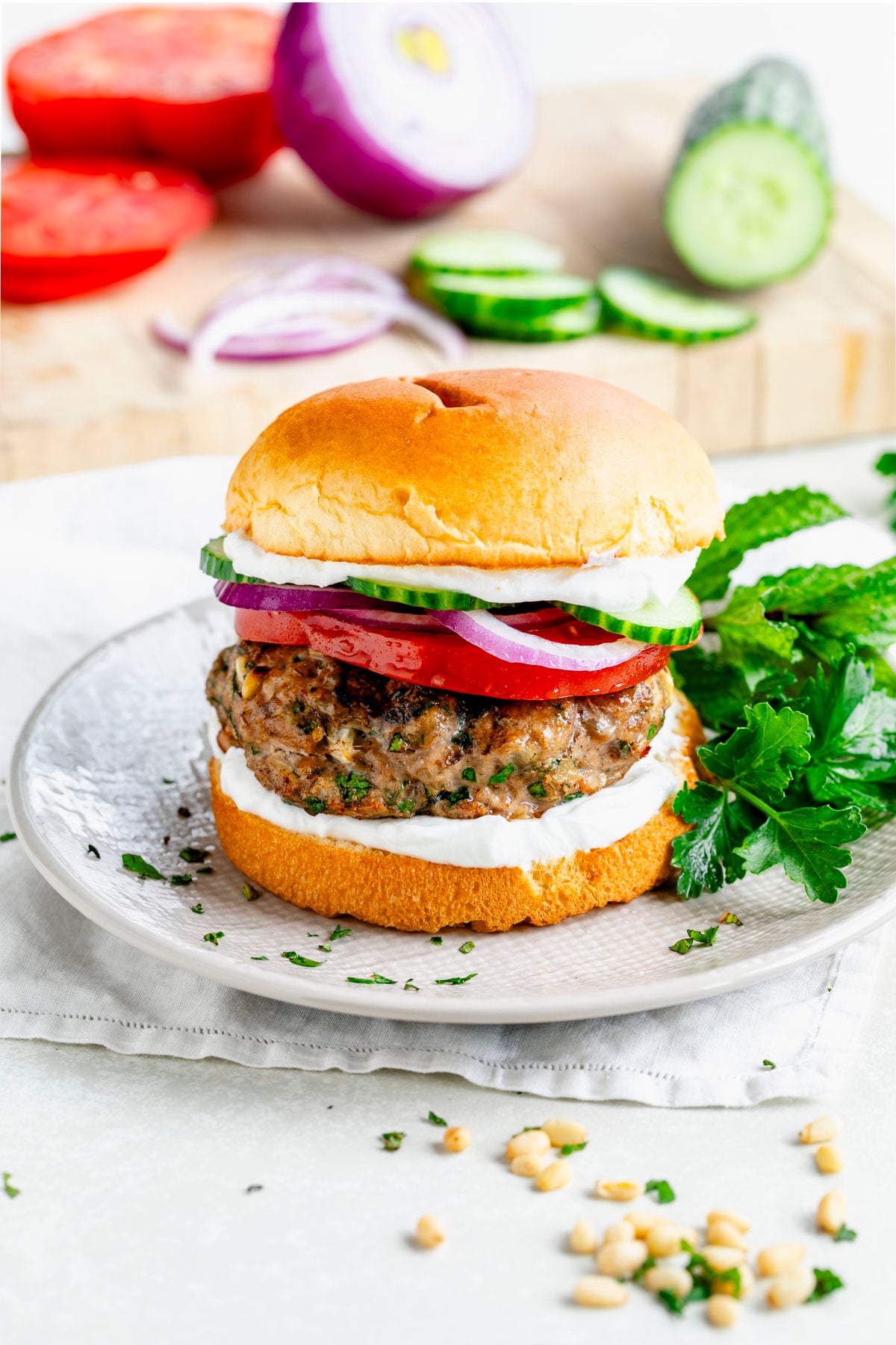 a turkey burger served with mediterranean style toppings like labneh, cucumbers, red onion, and mint
