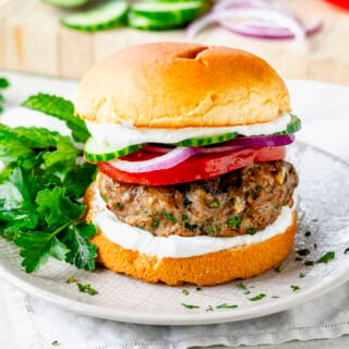 the middle eastern turkey burgers on a bun with cucumber, tomato and onion