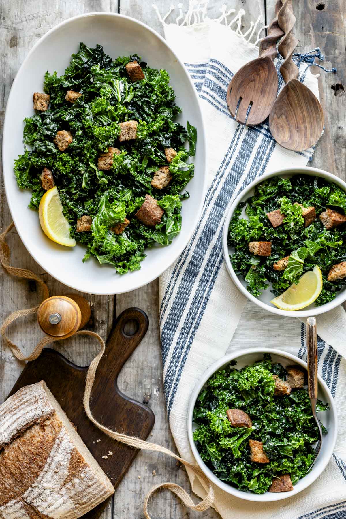 an oval bowl with overnight kale caesar with two servings dished up into individual bowls