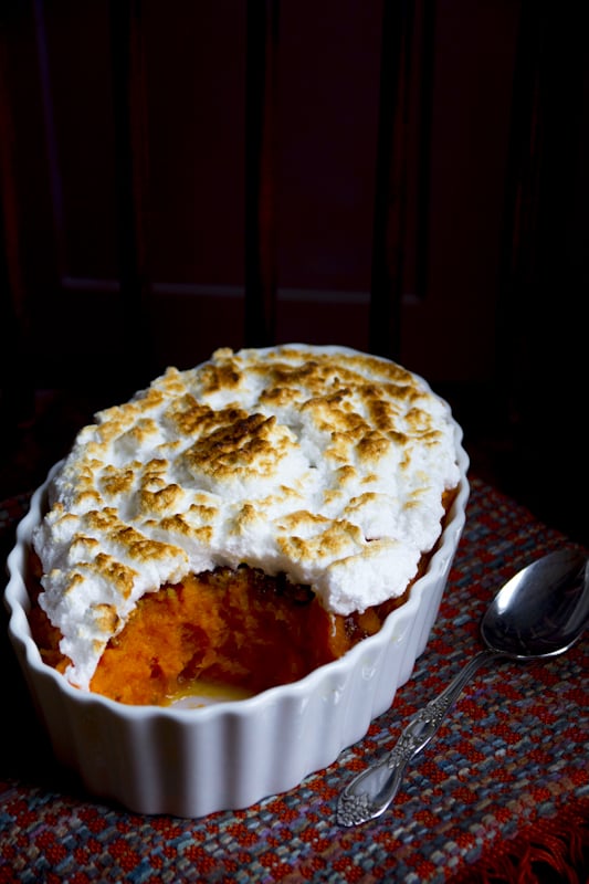 sweet potato casserole with browned meringue on top in front of a dark background