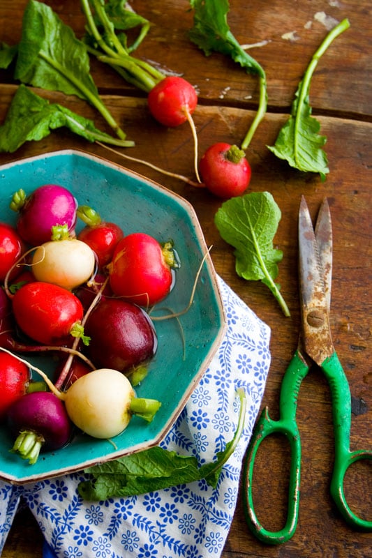 radishes in a bowl with green handled scissors